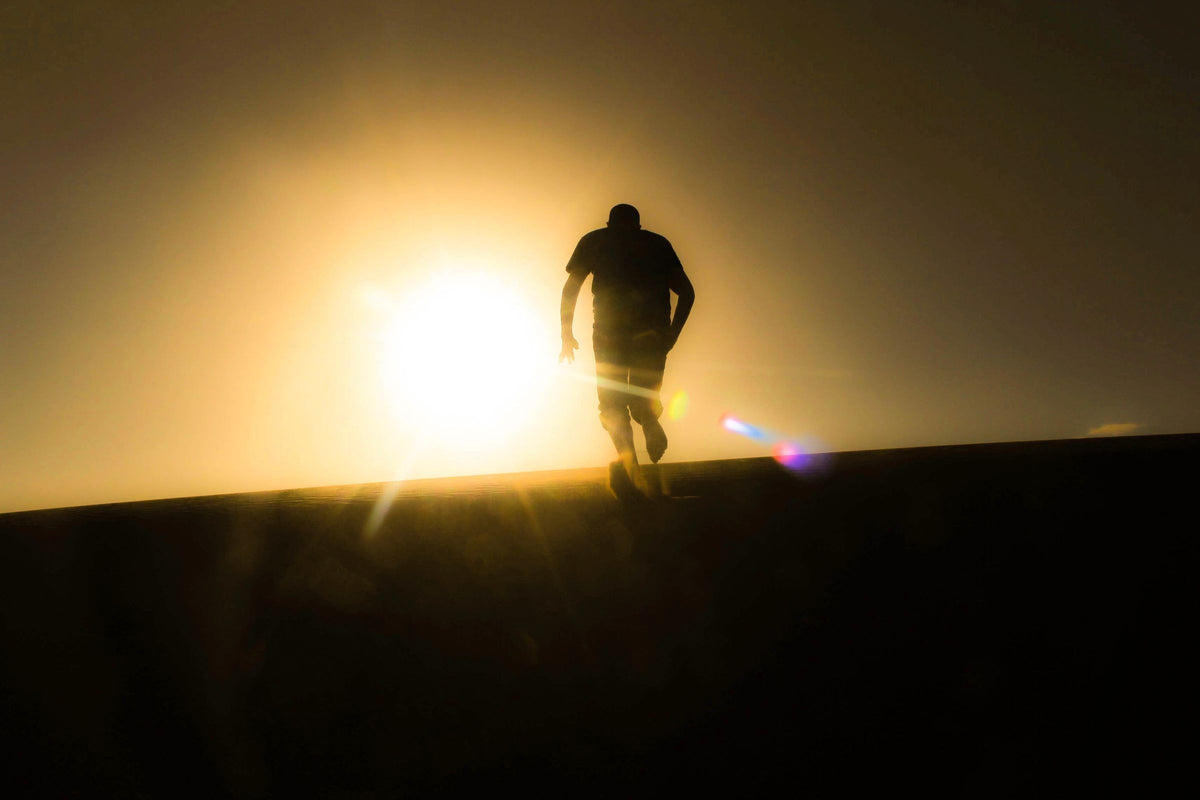 Man running uphill into the sunrise